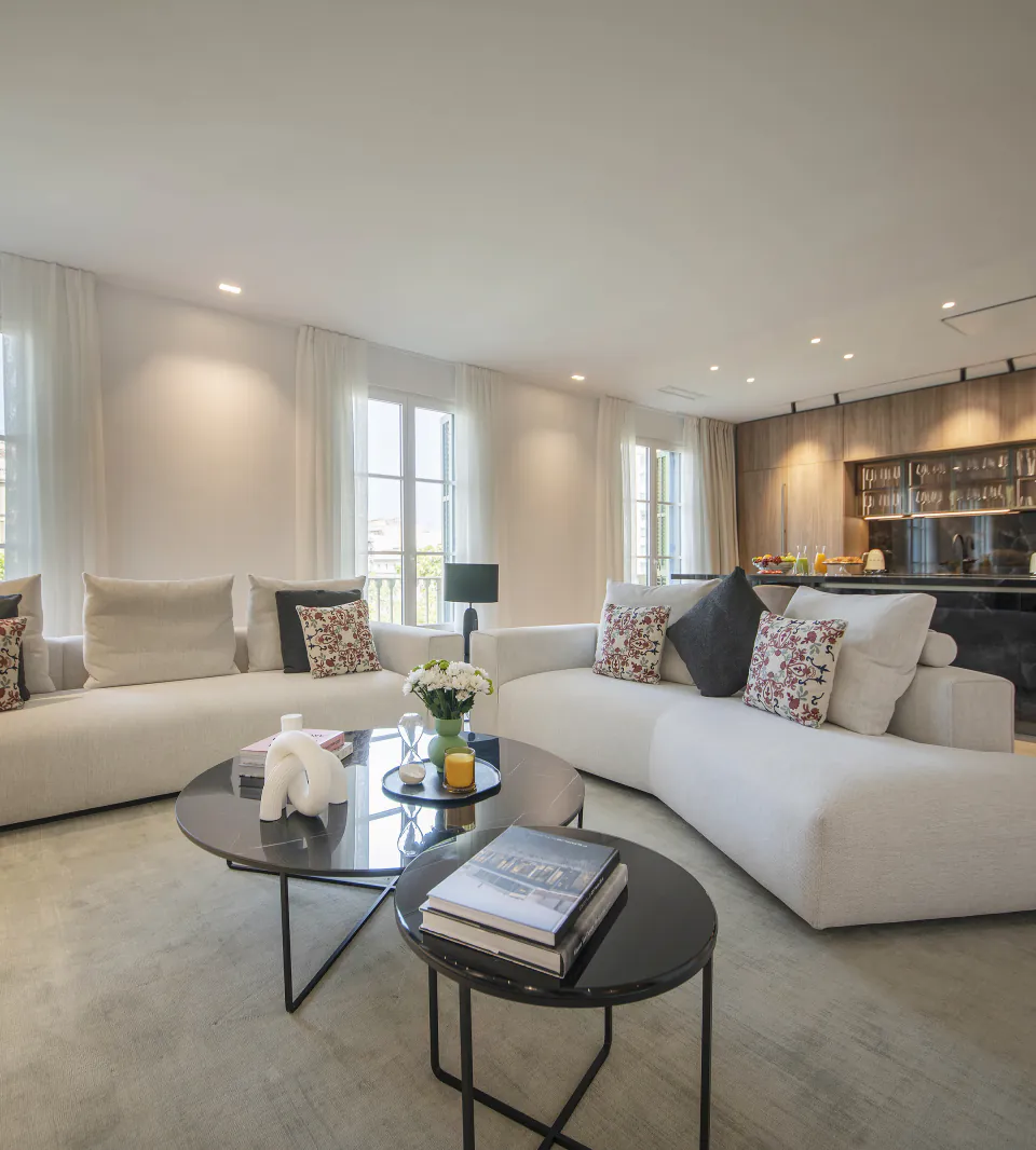 Sala d’estar de Suite Prestige amb sofàs clars, finestrals i cuina oberta