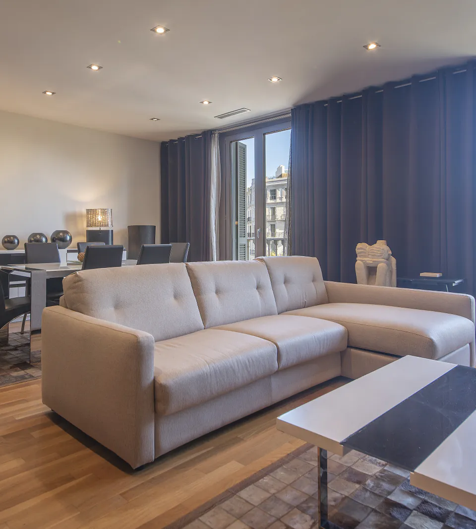 Sala d’estar i menjador de Suite Sagrada al costat dels finestrals amb balcó de Passeig de Gràcia