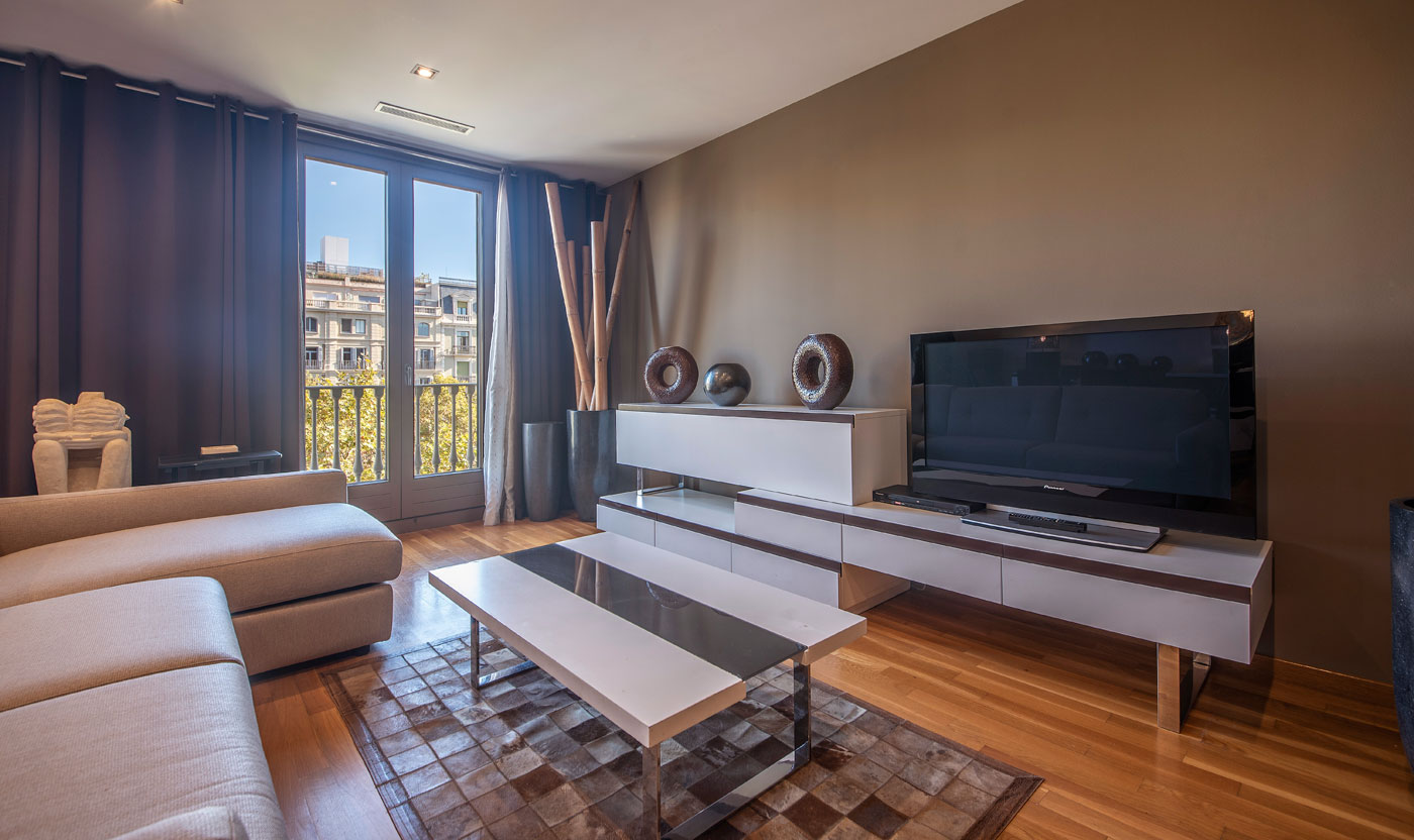 Sala de estar televisión y puertas de balcón en Suite Sagrada