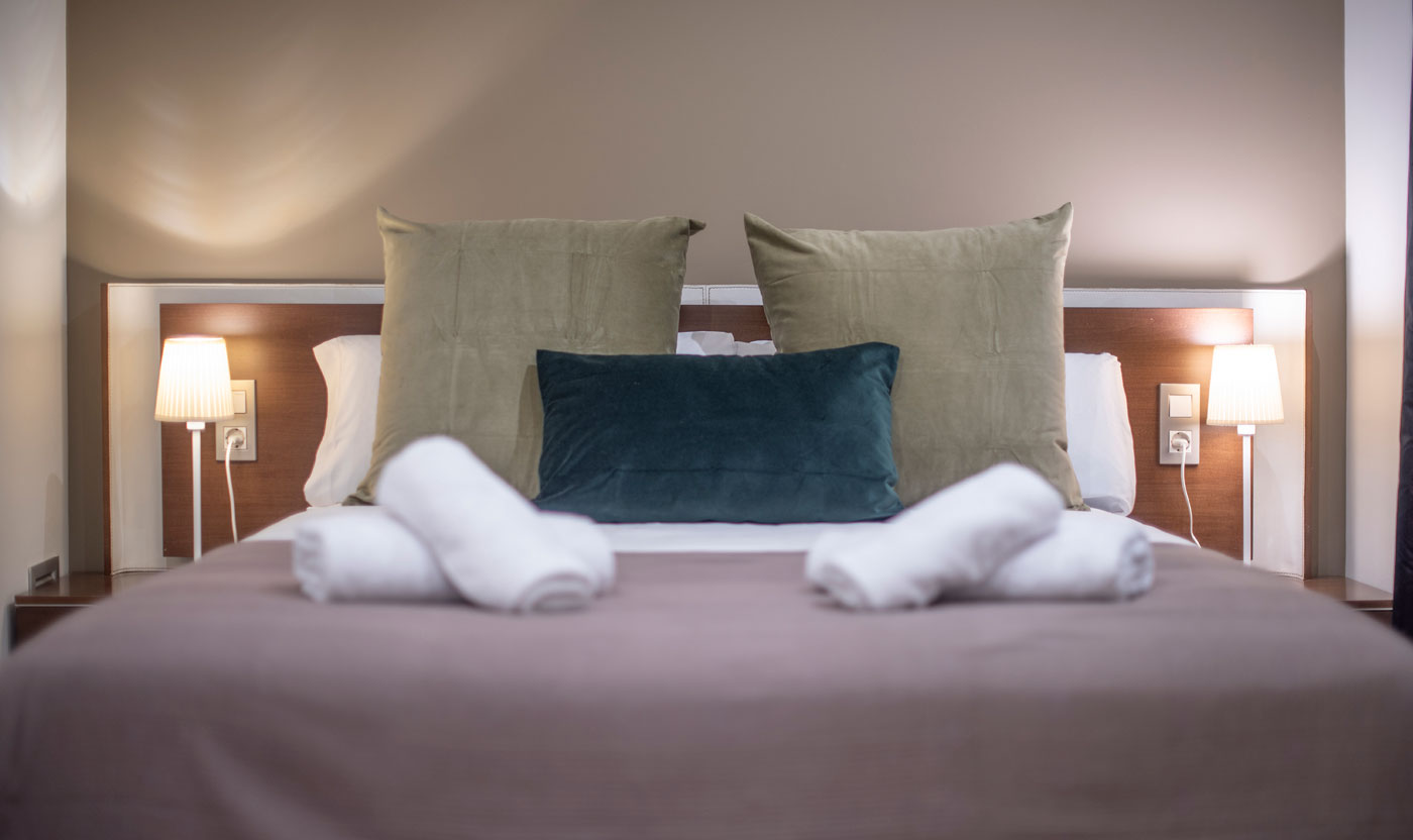 Cojines y toallas dobladas en la Suite Sagrada cama queen