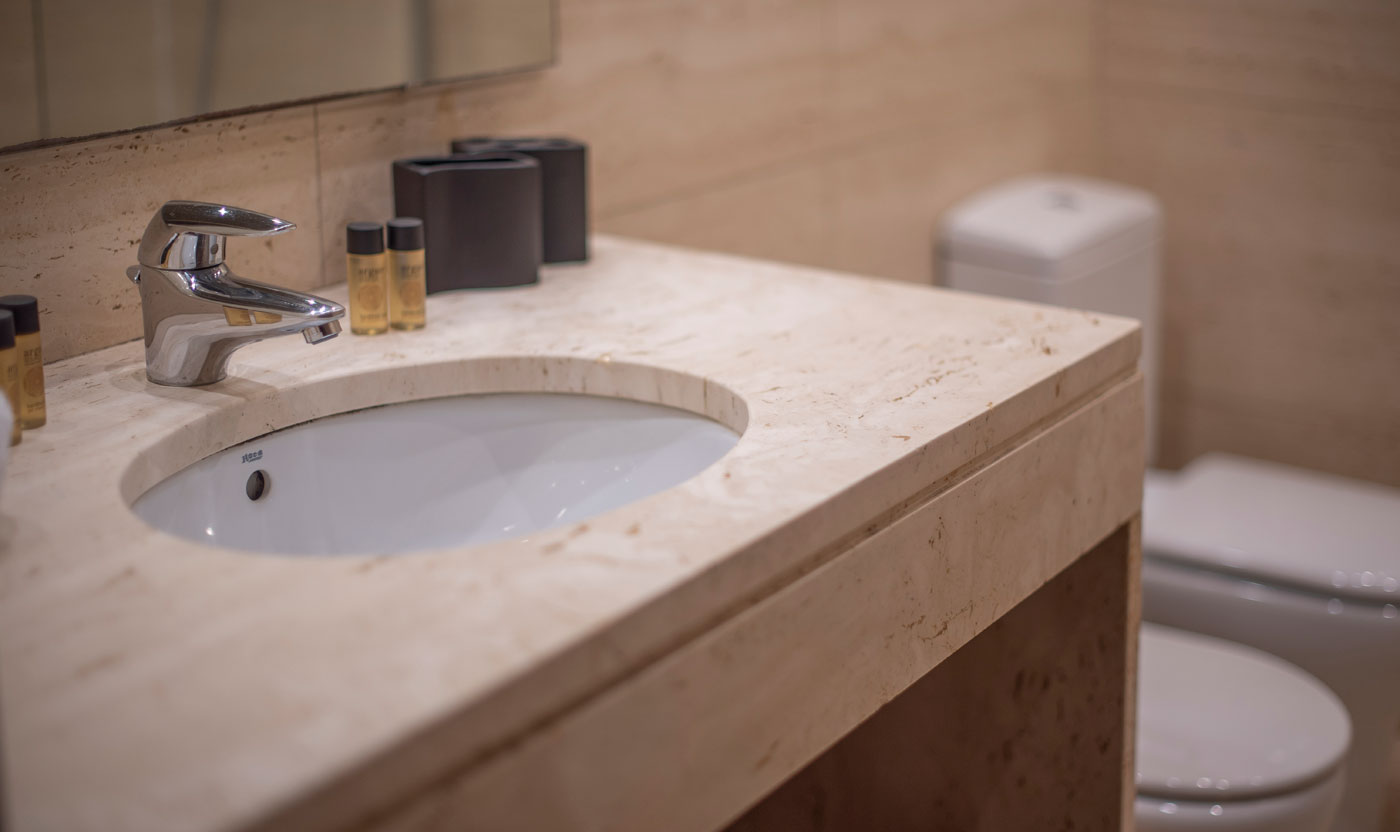 Lavabo de piedra y espejo en la suite Sagrada baño en suite