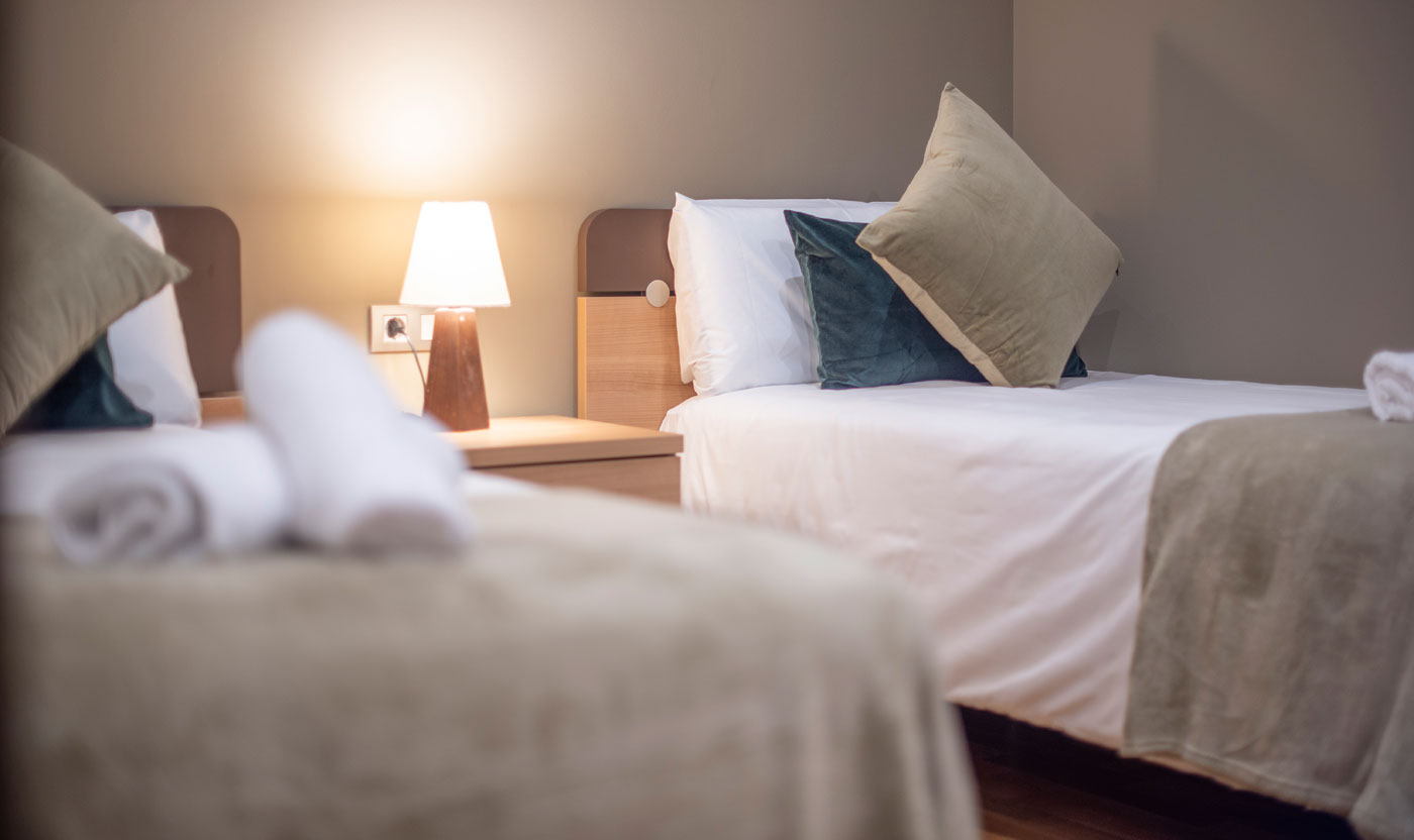 Camas individuales y lámpara de noche en la habitación doble Suite Sagrada