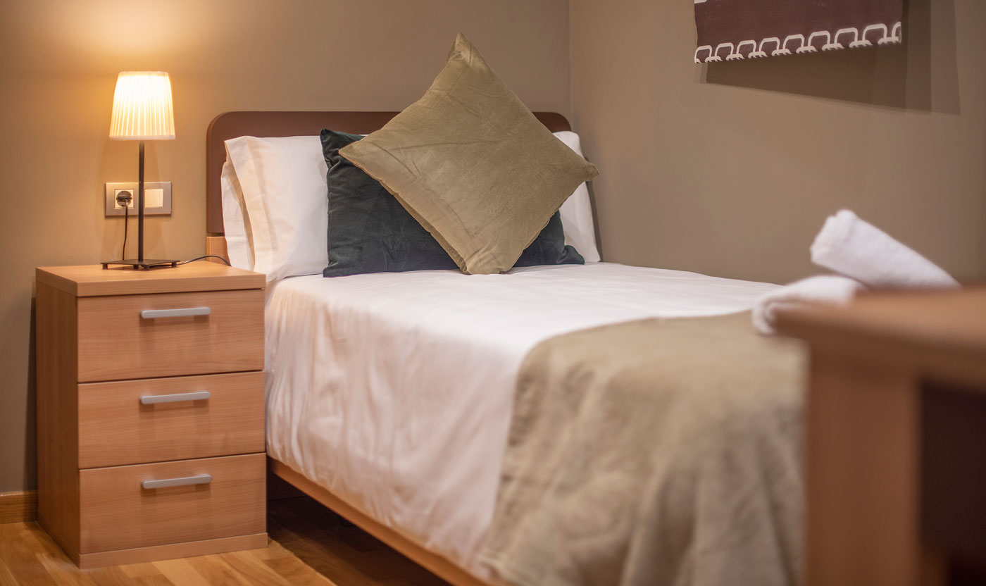 Cama individual y mesita de noche en Suite Sagrada
